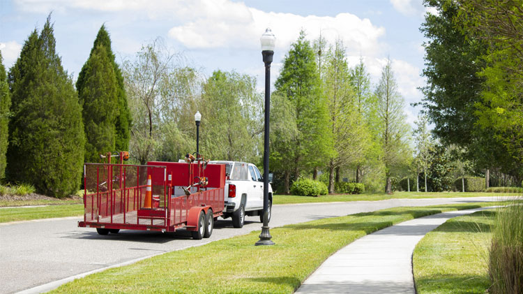 A lawn utility trailer driving down a residential road.