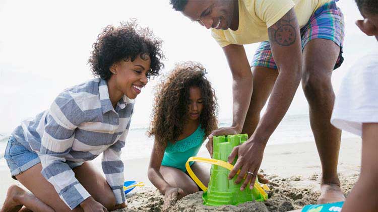 Family playing in the sand at the beach.