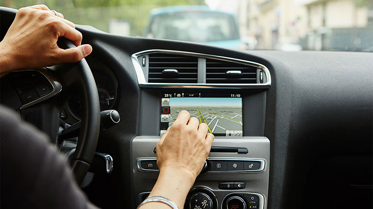 Driver using one of his car features, the onboard navigation system.