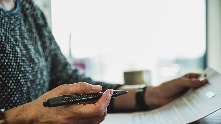 A woman with pen in hand reviews a will.